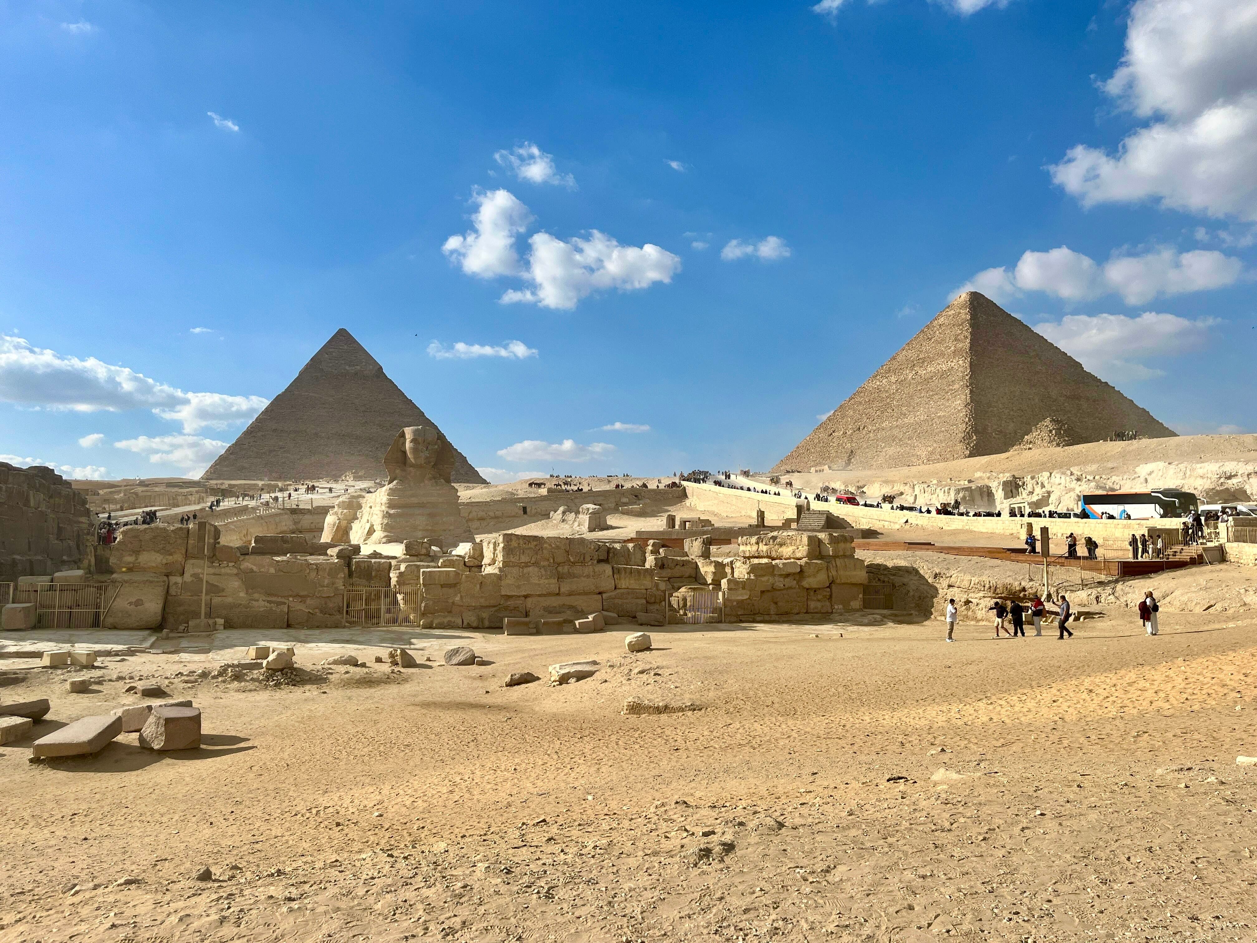 Panoramic view of the Giza Pyramids and Great Sphinx beneath a clear blue sky.