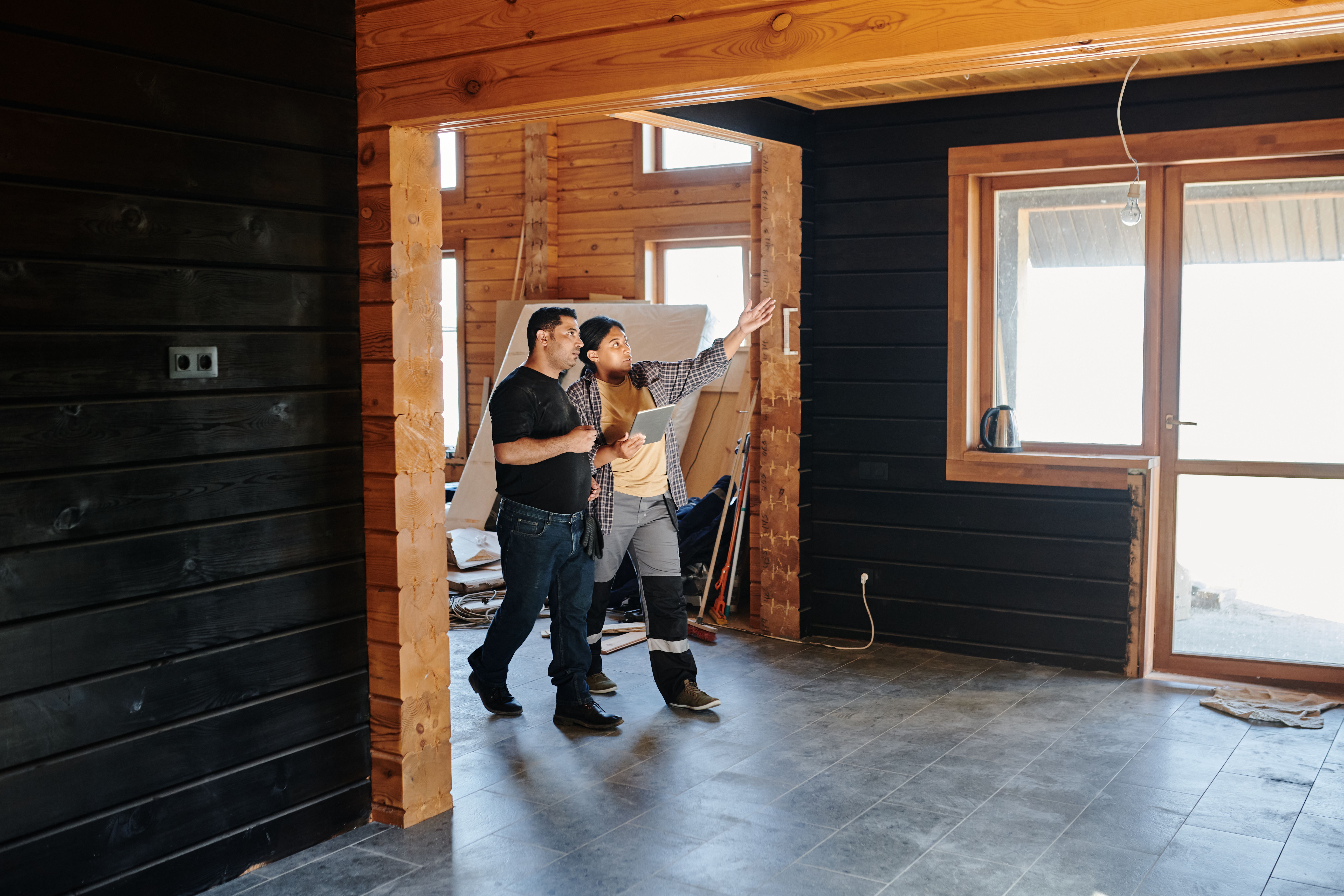 Homeowners discuss renovation plans inside a partially constructed house, representing project planning before construction begins.